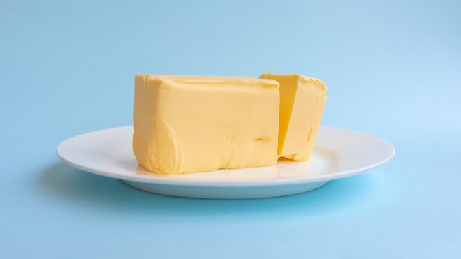 a stick of butter on a plate with a light blue background